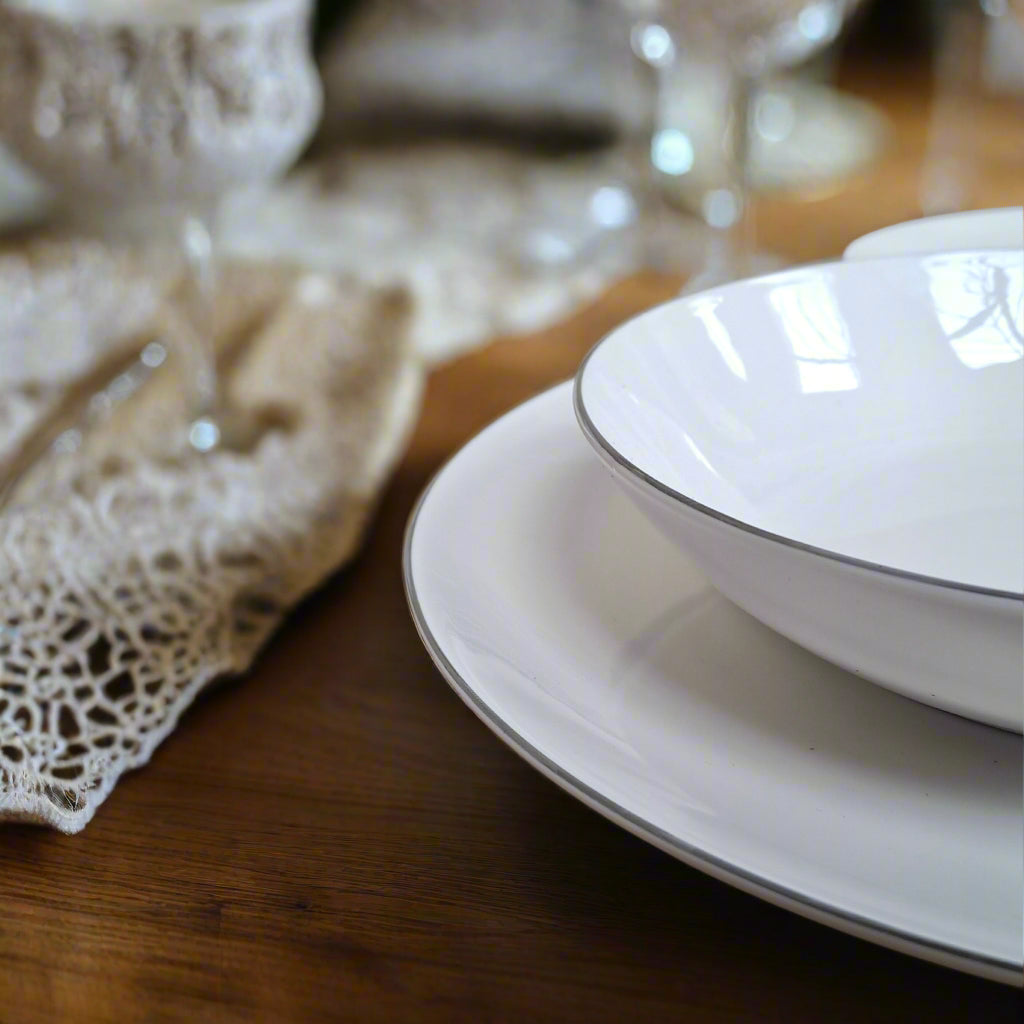 zbliżenie na krawędź biały talerzy wykończonych srebrnym dekorem filo platino od scapol tognana